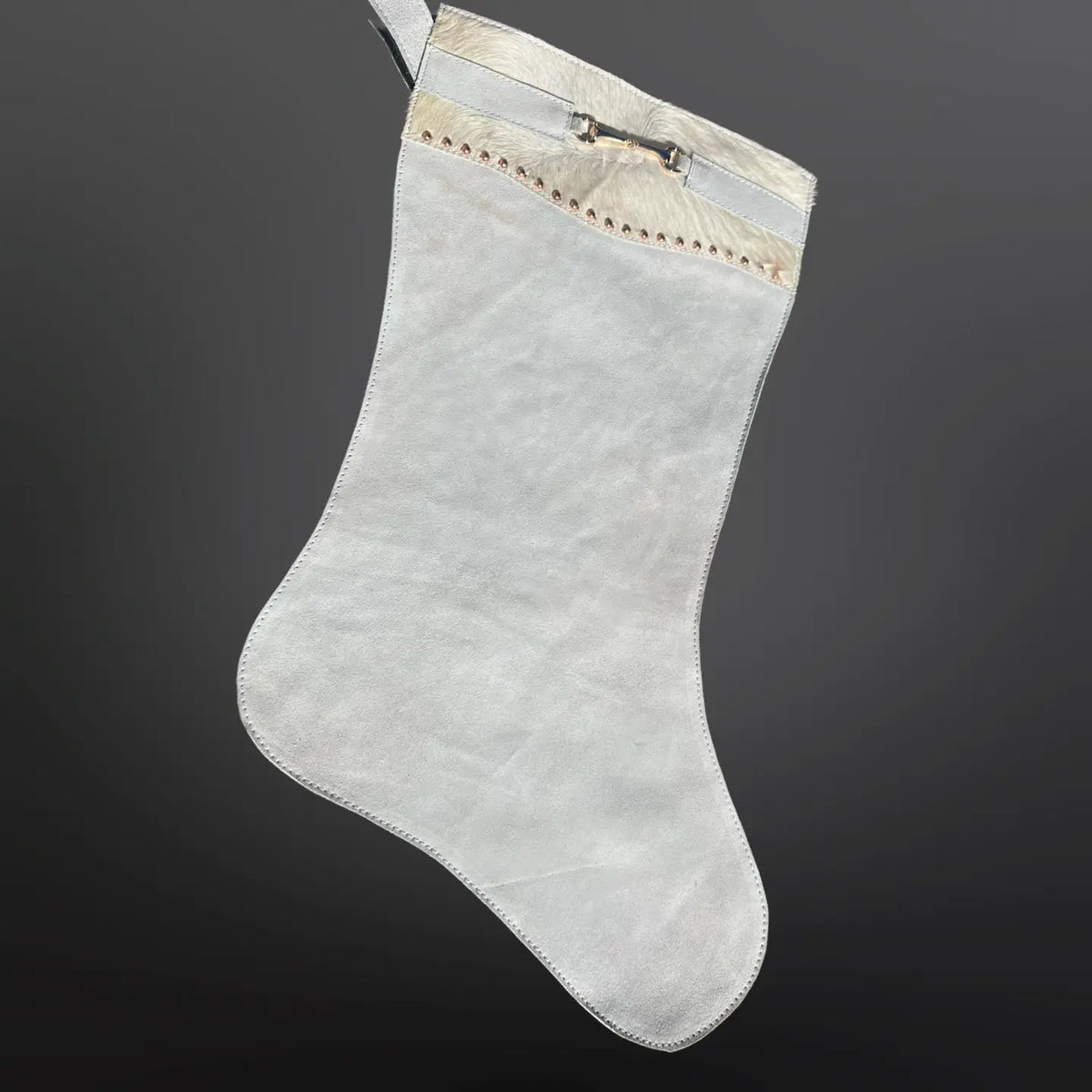 Light grey Christmas stocking with decorative trim on a dark gray background