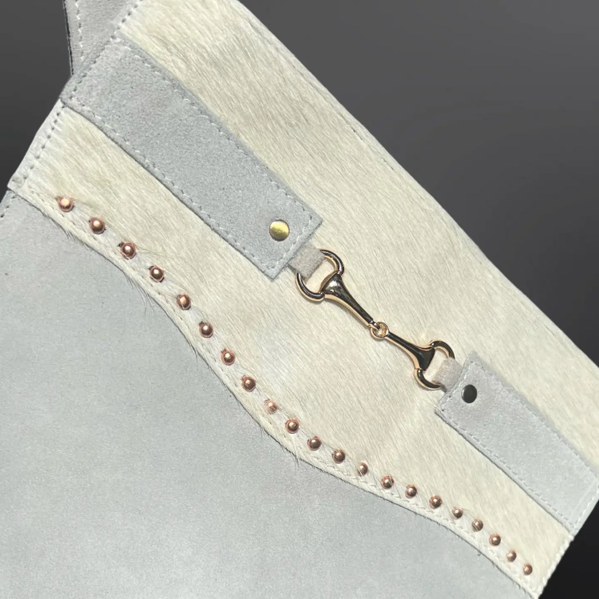 Close-up of a leather Christmas stocking with metallic buckle and decorative studs on a dark background