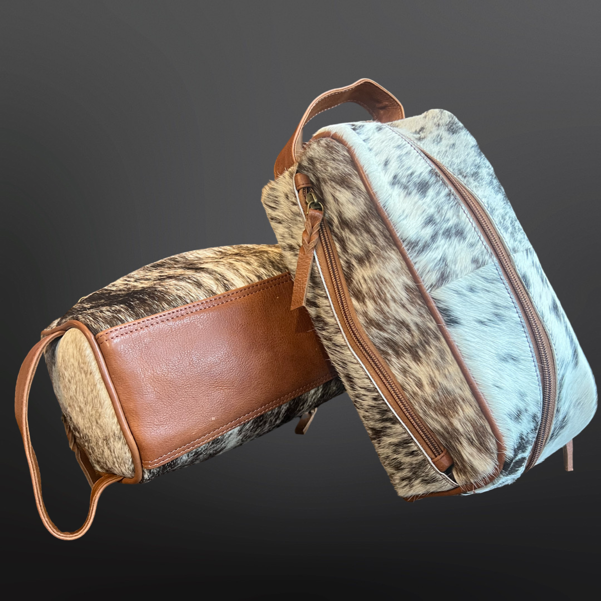Two leather bags with cowhide and brown accents on a dark background