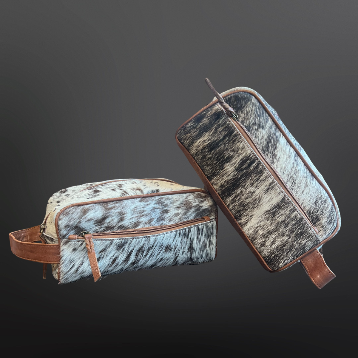 Two cowhide leather bags with brown leather straps on a dark background