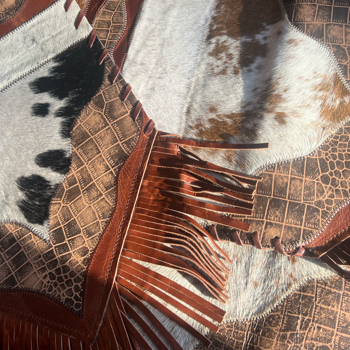 Close-up of a cowhide table runner with leather fringe