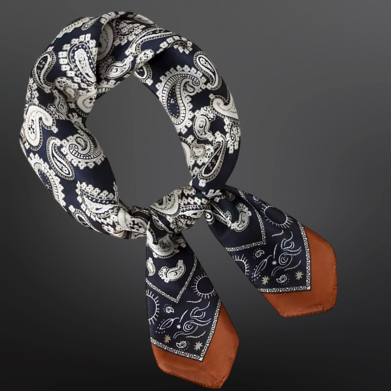 Navy blue and white paisley patterned scarf with brown ends on a dark background