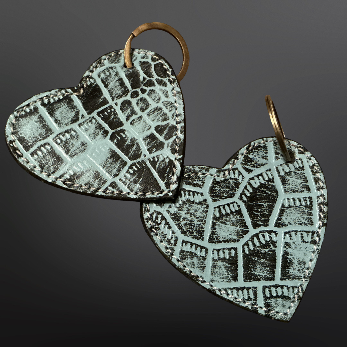 Heart-shaped keychains with textured pattern on a dark background