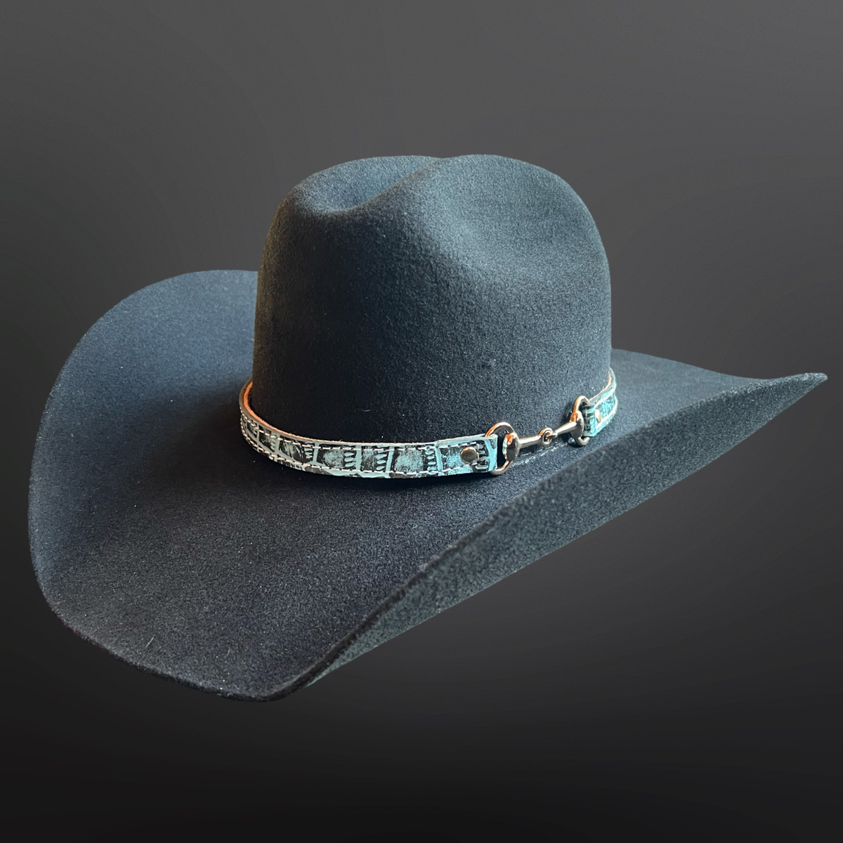 Dark gray cowboy hat with a decorative band on a dark background