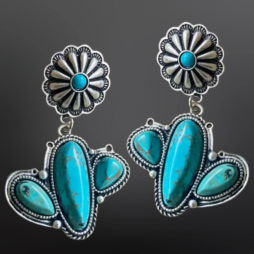 Pair of silver and turquoise earrings in a cactus design on a dark background