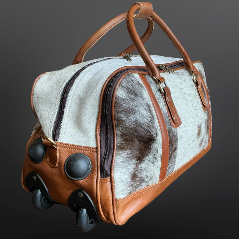 Travel wheeled bag with cowhide leather and brown leather accents on a dark background