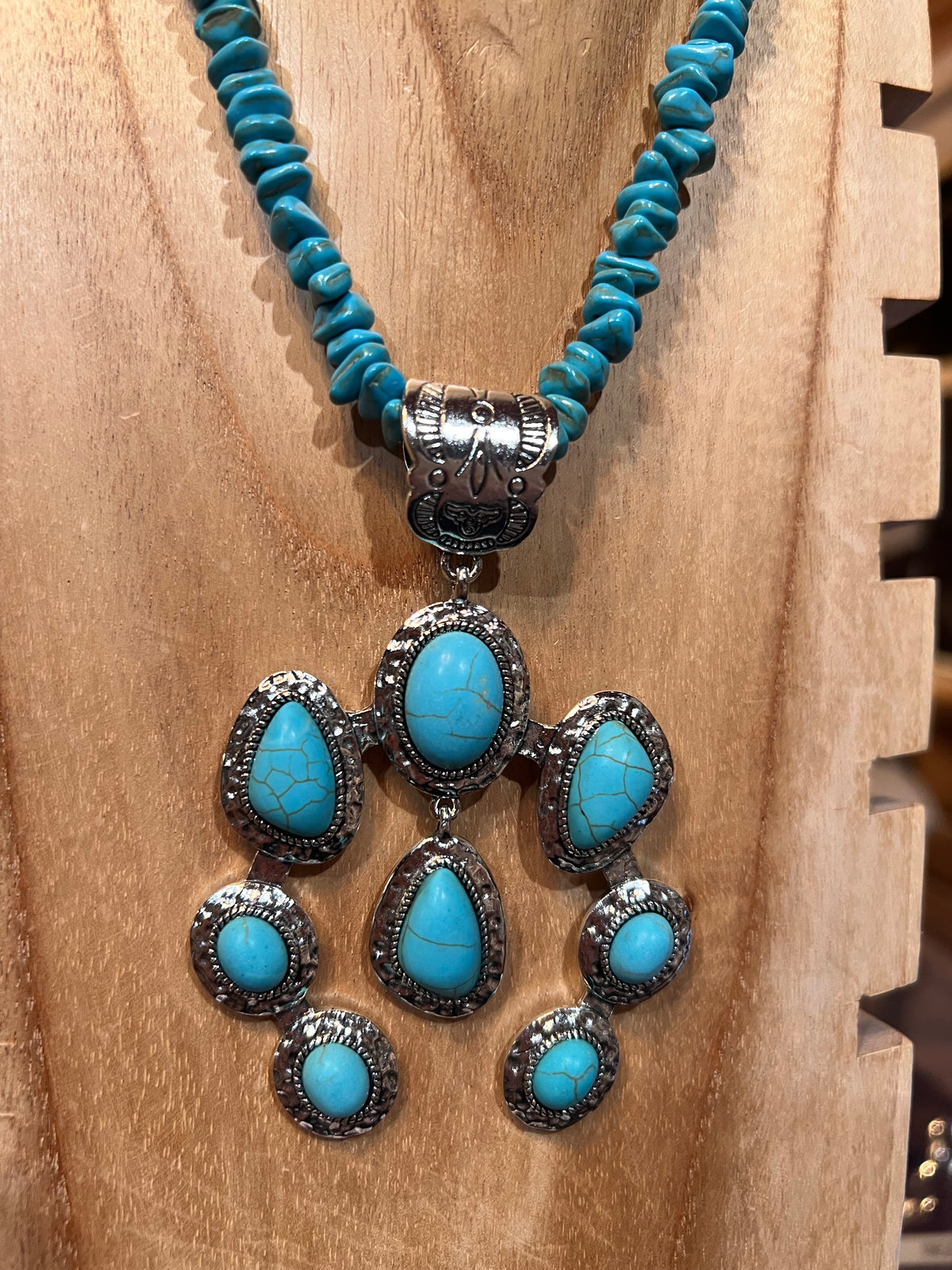 Turquoise beaded necklace with silver and turquoise stone pendants on a wooden surface