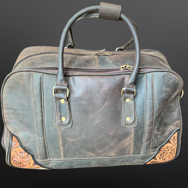 Brown leather duffel bag with decorative stitching on a dark background