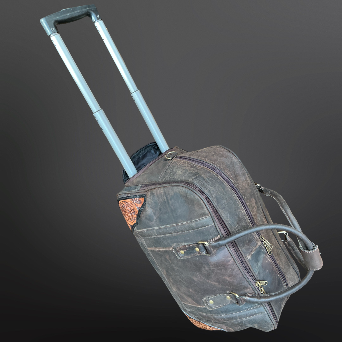 Brown leather duffel bag with wheels and tooled leather corners on a dark gray background