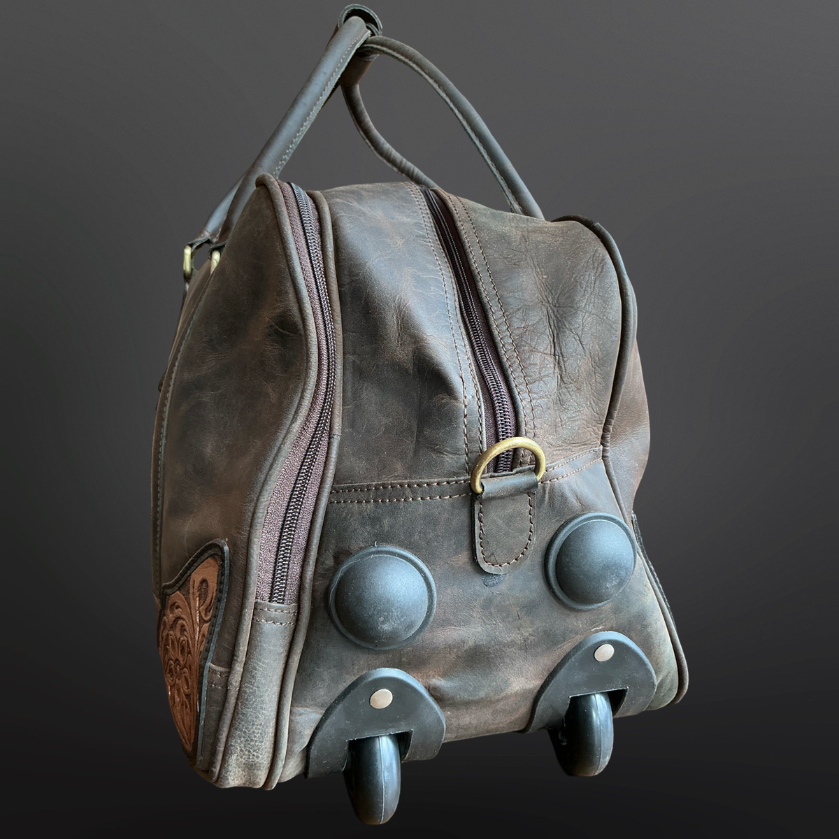 Distressed leather wheeled duffel bag showing the bottom of the bag on a dark background