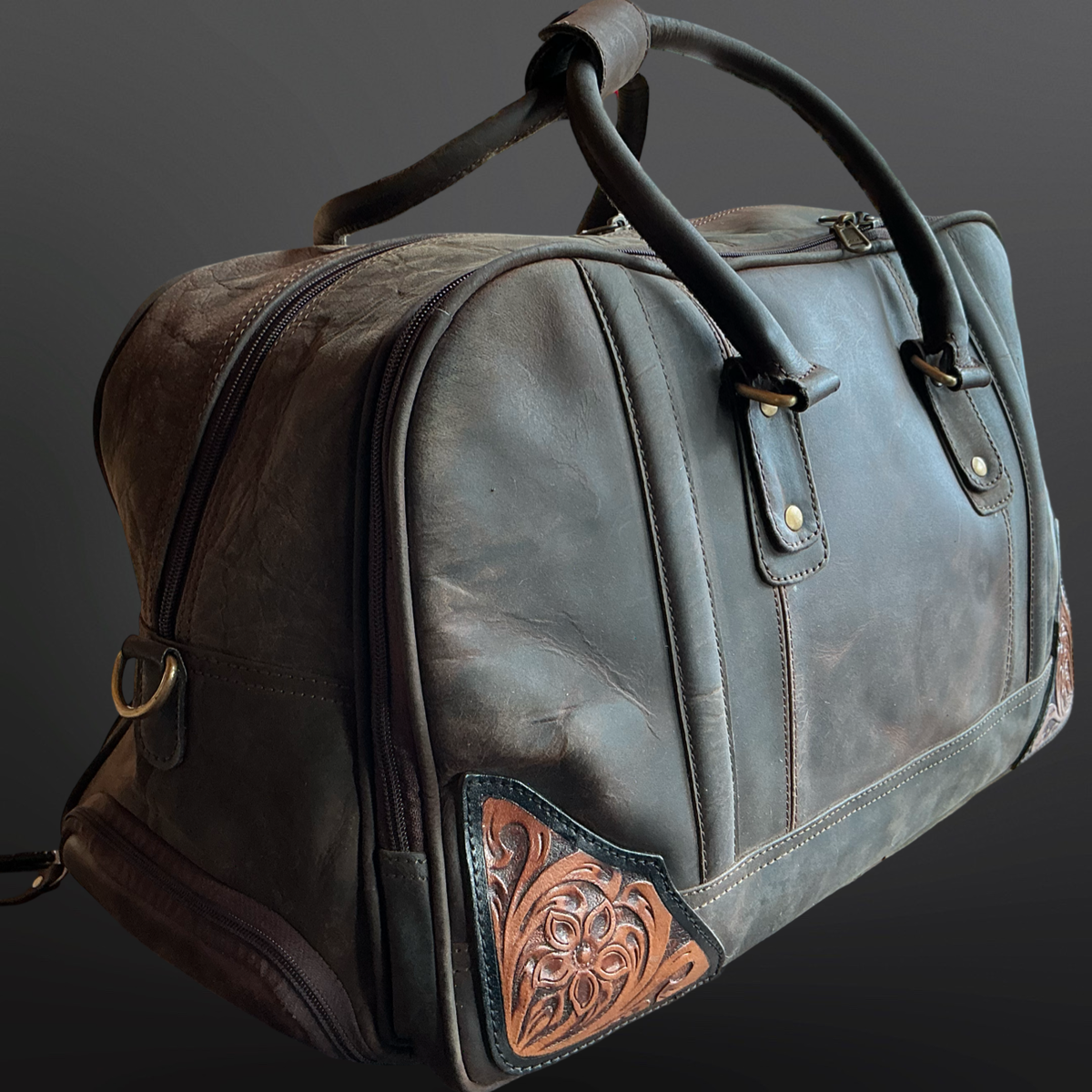 Leather duffel bag with decorative tooled stitching on a dark background