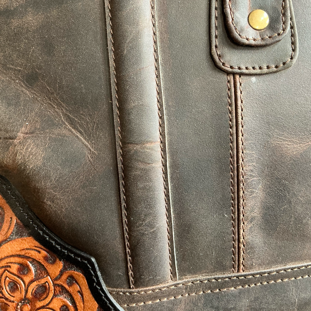 Close-up of a brown leather bag with western tooled leather details