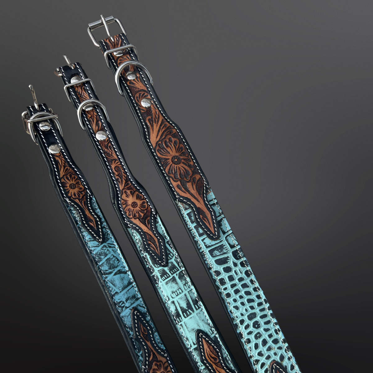 Three tooled leather dog collars with intricate designs on a dark background