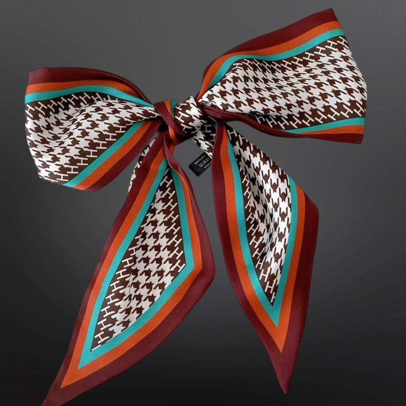 Patterned scarf tied into a bow with brown, orange, and blue colors on a dark background