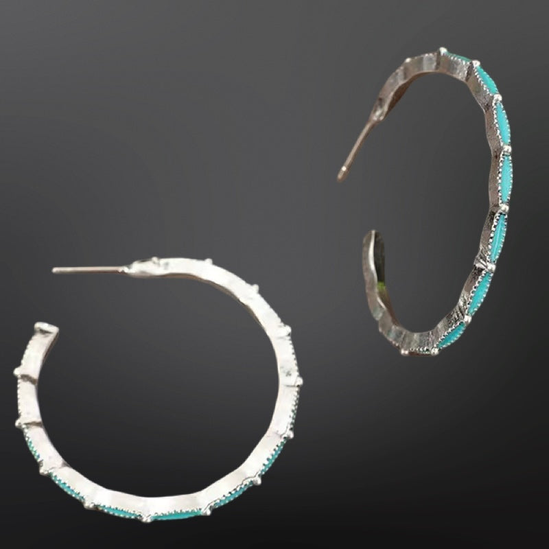 Pair of hoop earrings with turquoise stones on a dark background