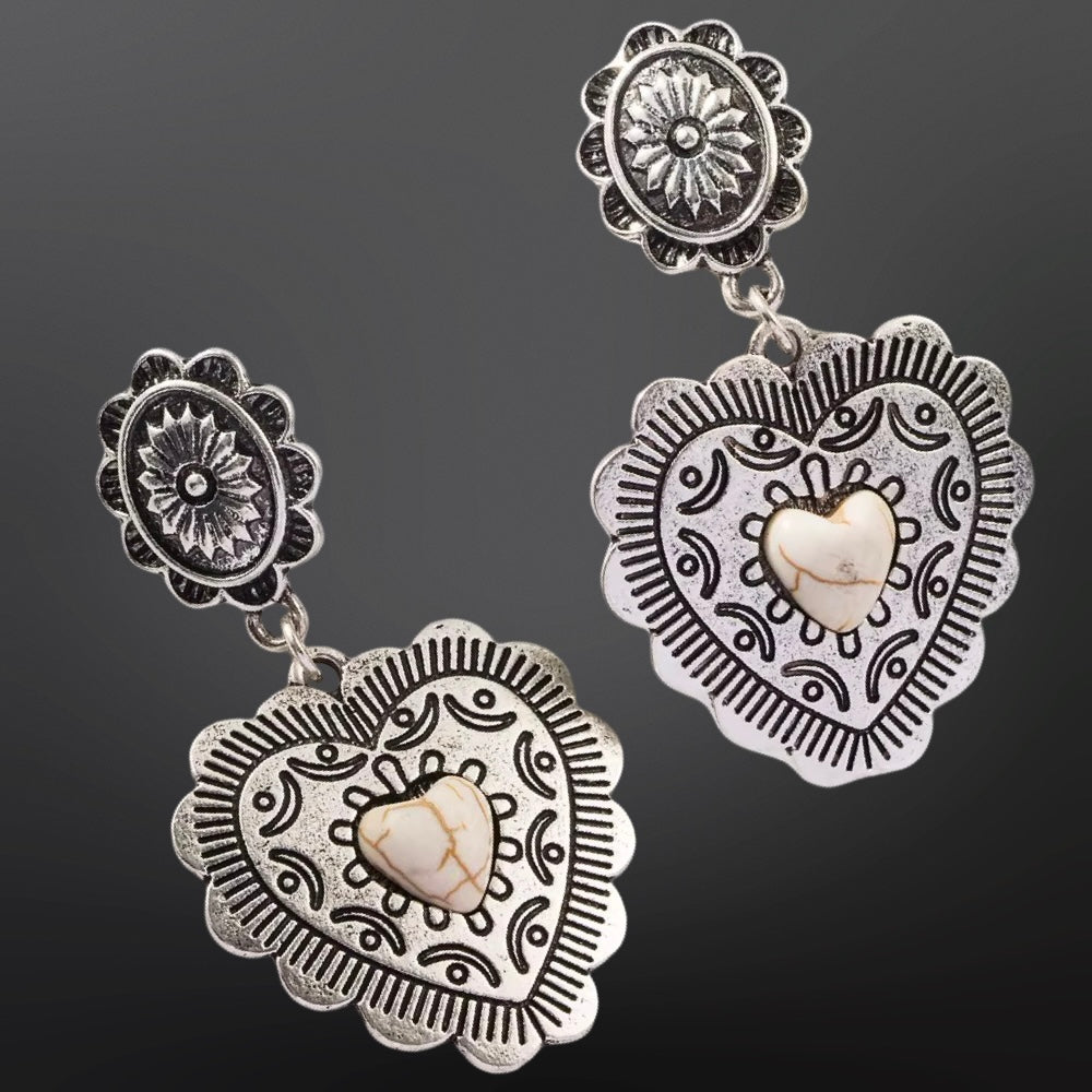 Silver earrings with heart designs on a dark background