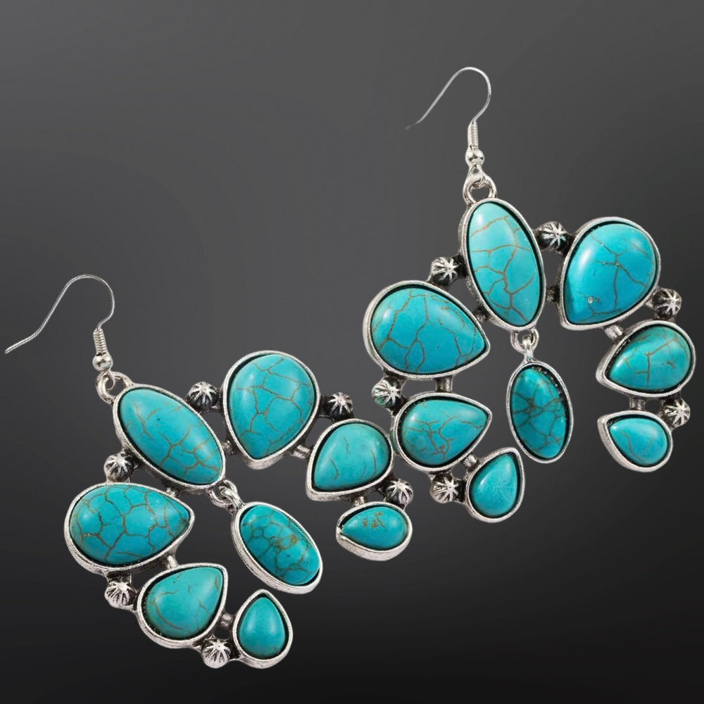 Turquoise earrings with silver accents on a dark background
