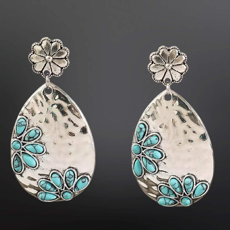 Teardrop-shaped earrings with turquoise stones and floral tops on a dark background