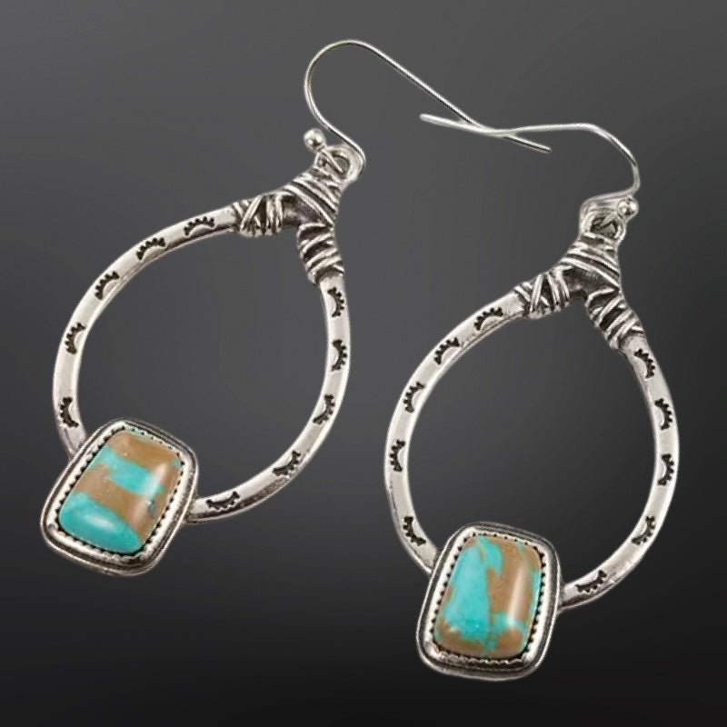 Silver hoop earrings with turquoise stones on a dark background