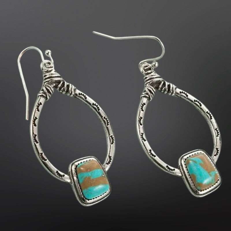 Silver hoop earrings with turquoise stones on a dark background